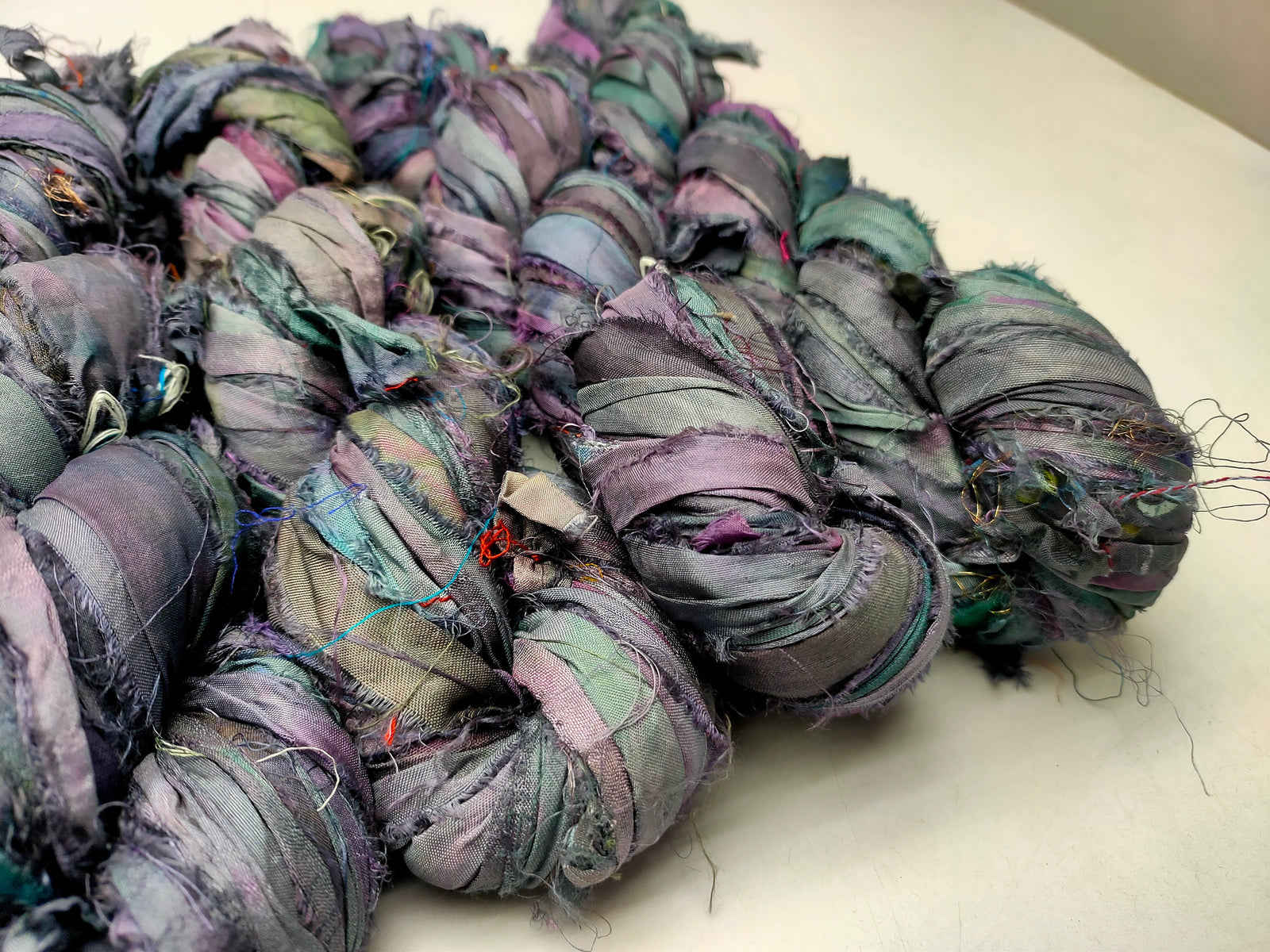 Recycled Sari silk Ribbon is the by-product of colorful saris that women wear in India. It is the loose ends of saris collected from industrial mills in India that is torn in stripes and sewn end 