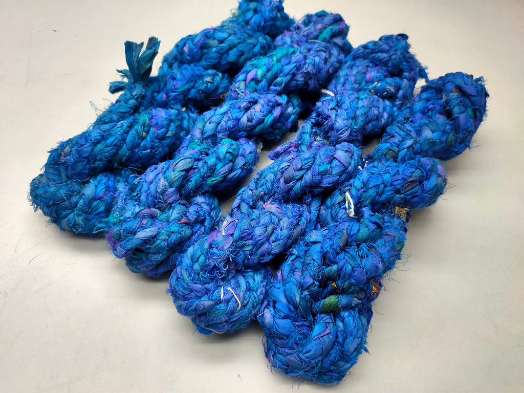 Braided Sari Silk Ribbon yarn is made of pure silk and is approximately an inch wide through out. Due to its handmade nature there might occasionally be variations in width. When silk fabric is cut and made into saris, wraps, and veils, there is always a bit left over. Rather than throw that waste fiber into the trash, it has been made into a beautiful, unique, soft yarn..!! Direct from India, this yarn is a truly recycled product. It is a bulky weight and is soft and easy to knit or croc