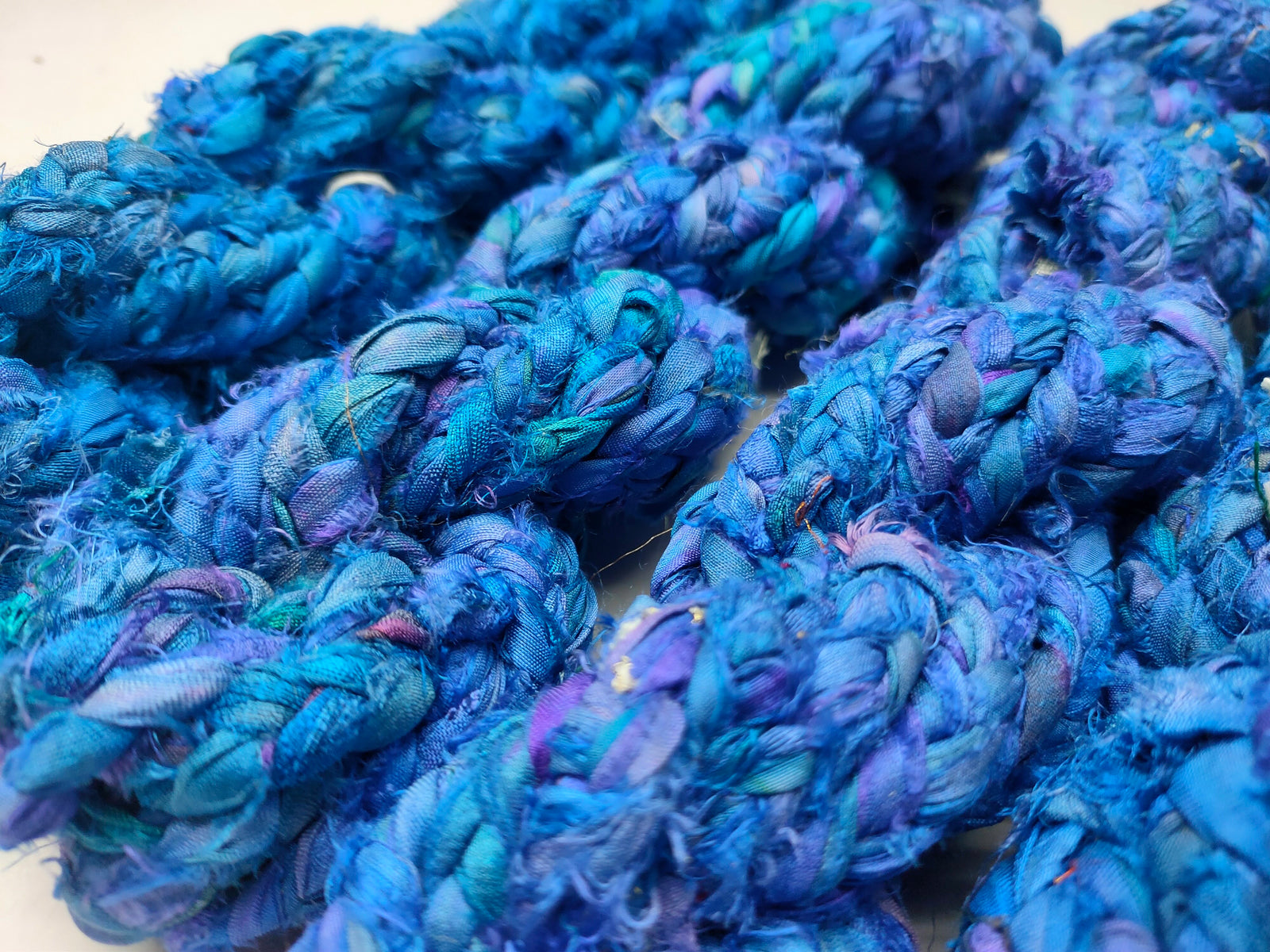 Braided Sari Silk Ribbon yarn is made of pure silk and is approximately an inch wide through out. Due to its handmade nature there might occasionally be variations in width. When silk fabric is cut and made into saris, wraps, and veils, there is always a bit left over. Rather than throw that waste fiber into the trash, it has been made into a beautiful, unique, soft yarn..!! Direct from India, this yarn is a truly recycled product. It is a bulky weight and is soft and easy to knit or croc