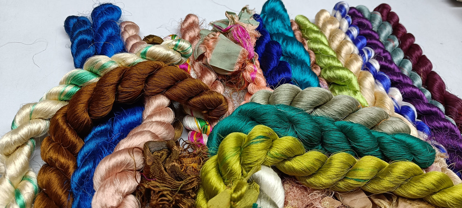 Sari Silk Fiber - Jewels Tone is available in assorted colorways, and is braided! They are the strongest natural roving fibers and are spun into a wonderful yarn used for knitting and weaving! The Colorful Sari Silk Thrums have a lovely draping quality. The fiber is a smooth filament and the fabric out of it is comfortable against the skin. Silk is a natural protein fiber. These roving fibers are well known for its shine, lustre and tensile strength.
