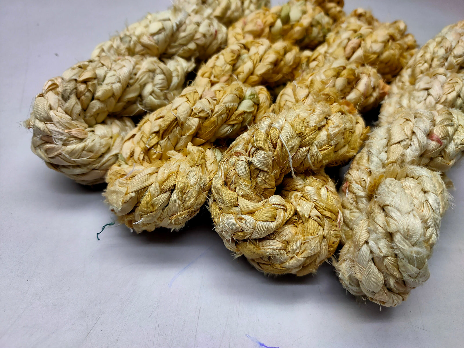 Braided yarn is made of pure silk and is approximately an inch wide through out. Due to its handmade nature there might occasionally be variations in width. When silk fabric is cut and made into saris, wraps, and veils, there is always a bit left over. Rather than throw that waste fiber into the trash, it has been made into a beautiful, unique, soft yarn..!! Direct from India, this yarn is a truly recycled product. It is a bulky weight and is soft and easy to knit or crochet.