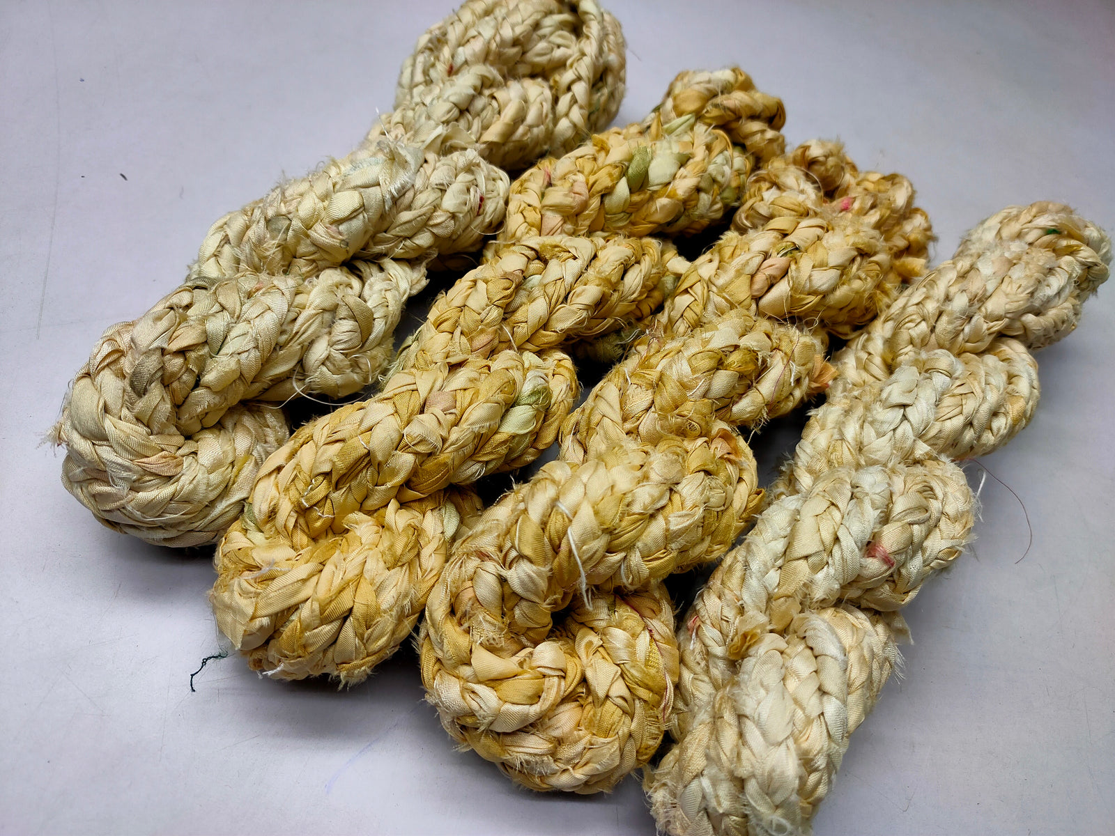 Braided yarn is made of pure silk and is approximately an inch wide through out. Due to its handmade nature there might occasionally be variations in width. When silk fabric is cut and made into saris, wraps, and veils, there is always a bit left over. Rather than throw that waste fiber into the trash, it has been made into a beautiful, unique, soft yarn..!! Direct from India, this yarn is a truly recycled product. It is a bulky weight and is soft and easy to knit or crochet.