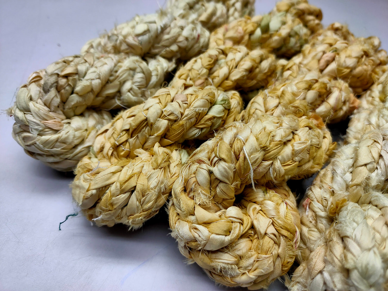 Braided yarn is made of pure silk and is approximately an inch wide through out. Due to its handmade nature there might occasionally be variations in width. When silk fabric is cut and made into saris, wraps, and veils, there is always a bit left over. Rather than throw that waste fiber into the trash, it has been made into a beautiful, unique, soft yarn..!! Direct from India, this yarn is a truly recycled product. It is a bulky weight and is soft and easy to knit or crochet.