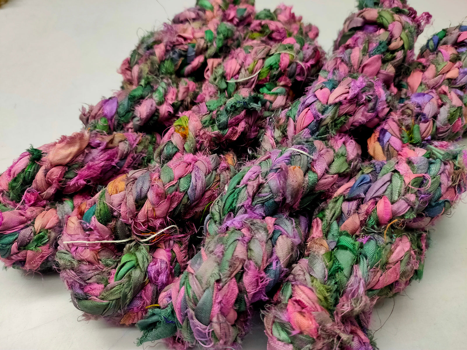 Braided Sari Silk Ribbon yarn is made of pure silk and is approximately an inch wide through out. Due to its handmade nature there might occasionally be variations in width. When silk fabric is cut and made into saris, wraps, and veils, there is always a bit left over. Rather than throw that waste fiber into the trash, it has been made into a beautiful, unique, soft yarn..!! Direct from India, this yarn is a truly recycled product. It is a bulky weight and is soft and easy to knit or crochet.