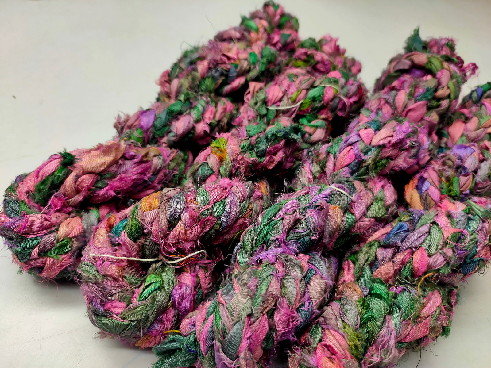 Braided Sari Silk Ribbon yarn is made of pure silk and is approximately an inch wide through out. Due to its handmade nature there might occasionally be variations in width. When silk fabric is cut and made into saris, wraps, and veils, there is always a bit left over. Rather than throw that waste fiber into the trash, it has been made into a beautiful, unique, soft yarn..!! Direct from India, this yarn is a truly recycled product. It is a bulky weight and is soft and easy to knit or crochet.