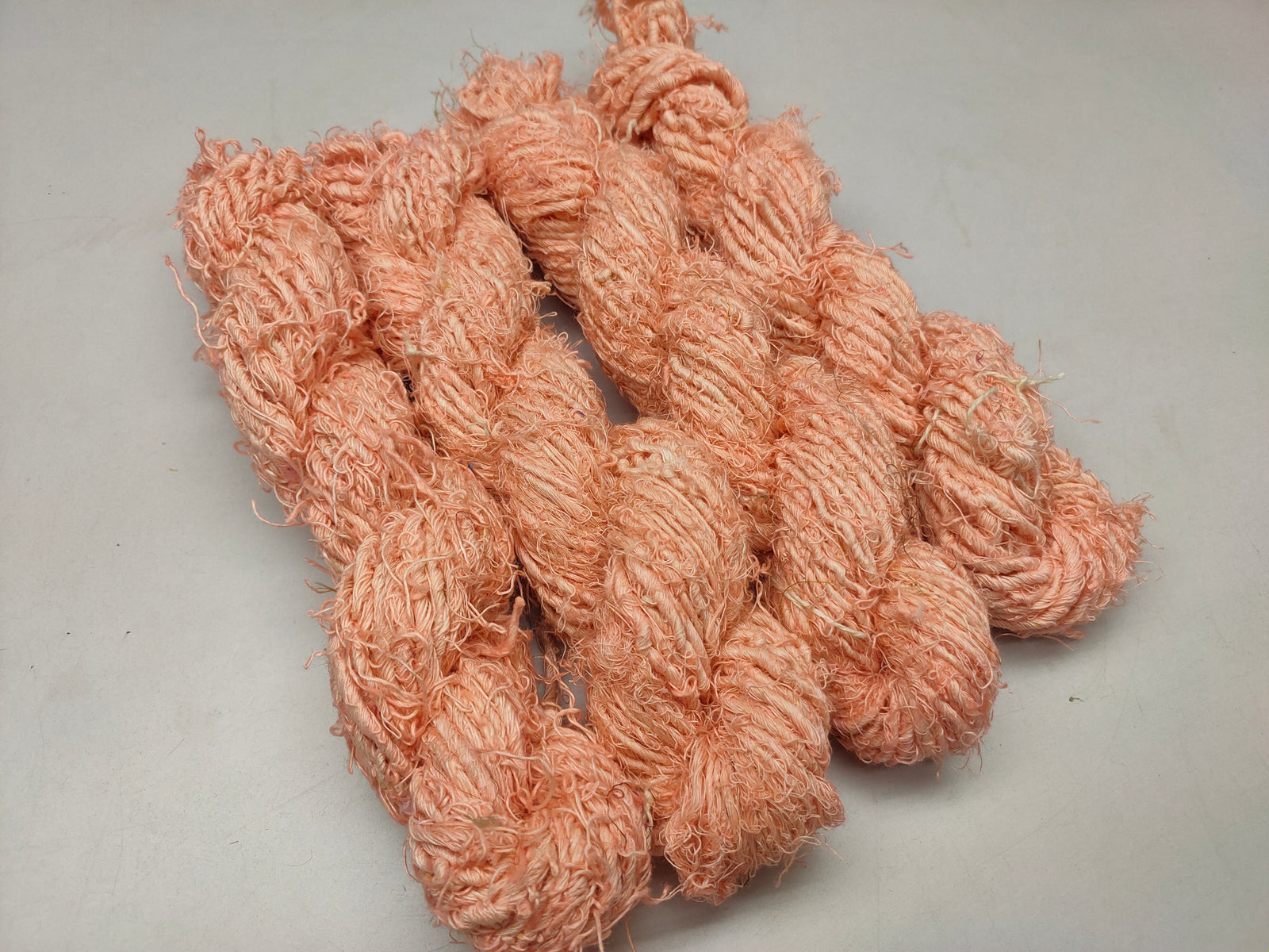 Recycled Linen Yarn - Peach is made from leftover or excessive warp/ weft thread on handlooms/ powerloom, to be specific the byproduct linen from industrial Linen weaving unit in India. This recycle yarn is hand-spun, using drop spindle helping women cooperatives to earn their livelihood