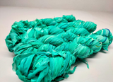 Chiffon Ribbon Yarn -  Turquoise Green is the by-product of saris that women wear in India. It is the loose ends of saris collected from industrial mills in India that is torn in stripes and sewn end to end to make beautiful and colorful ribbons. The vibrant colors and unique texture of these silk fabric, the Chiffon Ribbon are inspirational to designers, knitters, and artisans.