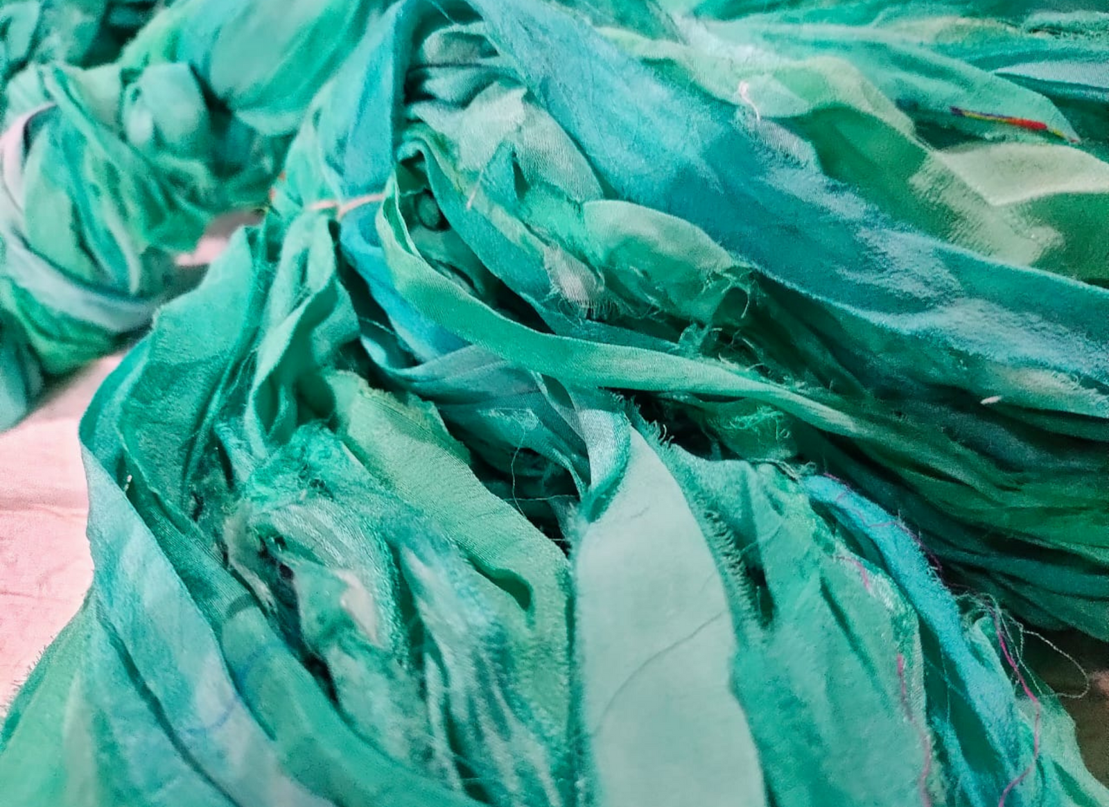 Chiffon Ribbon Yarn -  Turquoise Green is the by-product of saris that women wear in India. It is the loose ends of saris collected from industrial mills in India that is torn in stripes and sewn end to end to make beautiful and colorful ribbons. The vibrant colors and unique texture of these silk fabric, the Chiffon Ribbon are inspirational to designers, knitters, and artisans.